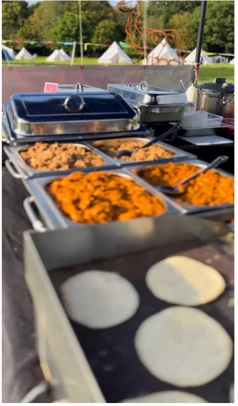 Outdoor catering buffet with silver chafing dishes and warm tortillas